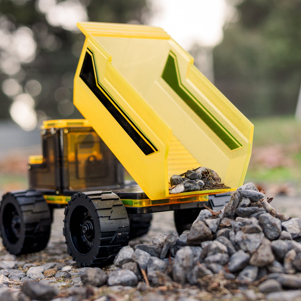 Magnetic tile dump truck with a yellow bed loaded with rocks outdoors