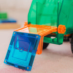 Toy recycling truck picking up a magnetic tile on a light background