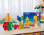 Colourful geometric tiles and Tile Tek expansion pack on a table with a white curtain background