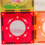 Two transparent  magnetic tiles with circular designs on a textured surface