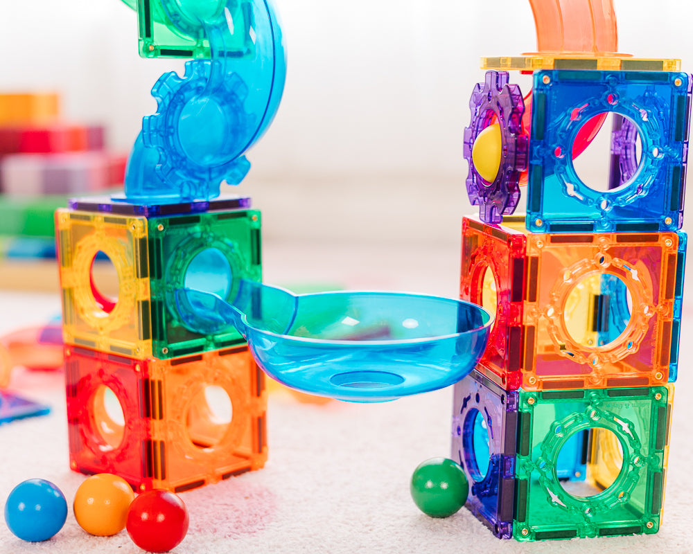 Colourful magnetic building blocks with a bowl and balls on a light background